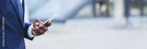Mobile Business App. Unrecognizable Black Man Entrepreneur Using Phone Standing Outdoors In City. Cropped, Selective Focus, Copy Space