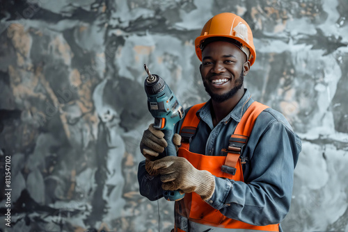 A smiling black construction worker holding a drill.