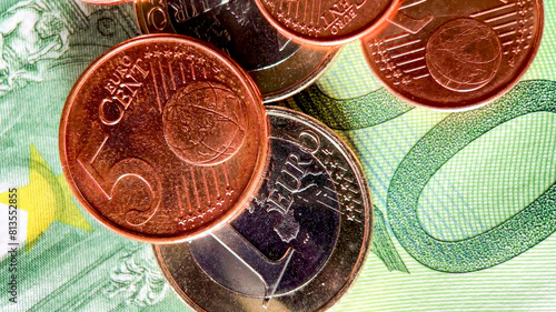 Close-up of assorted Euro coins on a colorful banknote background, related to finance, economy, European Union, and World Savings Day
