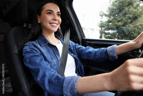 Woman with seatbelt holding steering wheel while driving her car