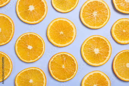 Slices of juicy orange on light blue background, flat lay