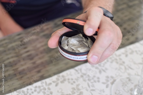 A man holds a box of snus. A box of snus pads replaces smokeless cigarettes. Swedish nicotine pouch.