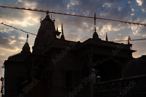 backlit shot of dramatic sunset sky and artistic hindu temple at evening from unique perspective