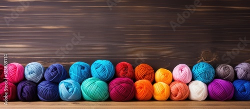 On a wooden surface there is a copy space image showcasing multicolored crochet hooks and vibrant balls of yarn