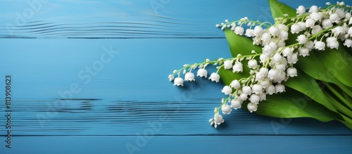 A flat lay image with a blue wooden background showcasing a bouquet of lilies of the valley. Copy space image. Place for adding text and design