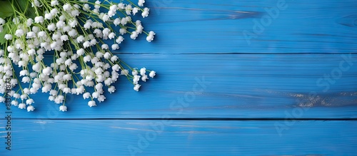 Blue wooden background with lilies of the valley and forget me nots providing ample copy space