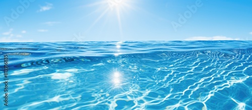 A serene outdoor swimming pool with crystal clear blue water reflects the sun s rays creating a captivating sun flare on its surface The backdrop showcases the mesmerizing blue water embellished with