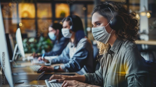 A pair of stylish employees wear protective face masks while working in a loft office, answering emails and managing marketing projects. Pandemic Covid-19 concept.