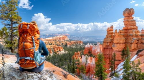 Rear view of a woman with a backpack overlooking the stunning Bryce Canyon landscape under blue skies with clouds.