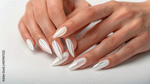 Close-up of elegant woman's hands showing off long almond-shaped nails with a shimmering white finish.