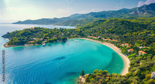 Aerial view of a beach in Greece, with turquoise water and lush greenery surrounding it, showcasing the picturesque setting on a Greek island