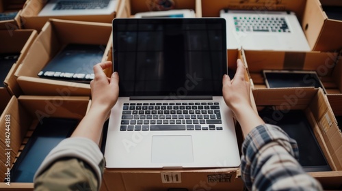 Recycling E-Waste: Woman Puts Old Laptop in Cardboard Box with Used Gadgets for Donation and Reuse