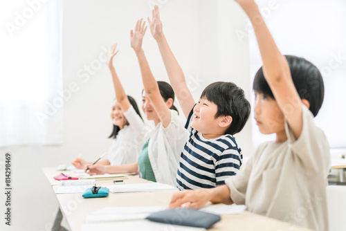 塾・学校の授業中に元気に挙手する小学生の男女生徒 