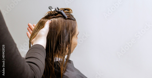 Woman professional hairdresser doing hair styling to client in beauty salon, applies balm to strengthen hair, stylist doing hair care procedures