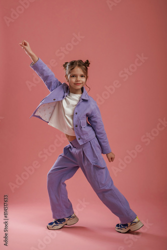 Dancing, having fun. Cute little girl is against pink background