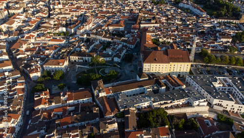 Aerial view of the charming historic streets of Évora, Portugal. Cobblestone roads wind past ancient buildings under the golden sunlight.