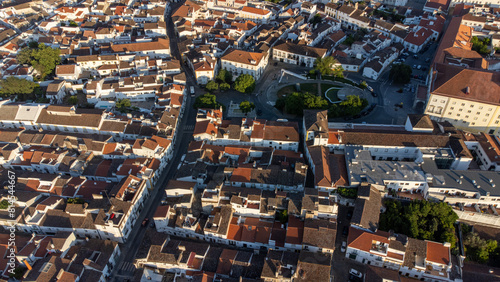 Aerial view of the charming historic streets of Évora, Portugal. Cobblestone roads wind past ancient buildings under the golden sunlight.