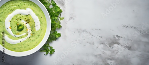 This is a top down view of a vegan cream soup made from green vegetables served in a grey bowl on a grey background In the image there is a panoramic view with copy space