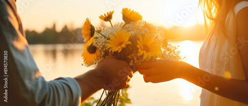 Person holds yellow and white flower bouquet under blue sky