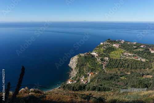 View at mediterranean coast with residential buildings to the distant Stromboli volcano on a hazy sunny day seen from Palmi, Calabria, Italy