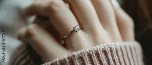 A delicate hand flaunts a beautiful diamond engagement ring on a finger.