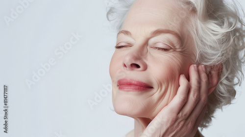 Older woman, radiating serenity with closed eyes, gently caresses her smooth skin, facial anti-aging
