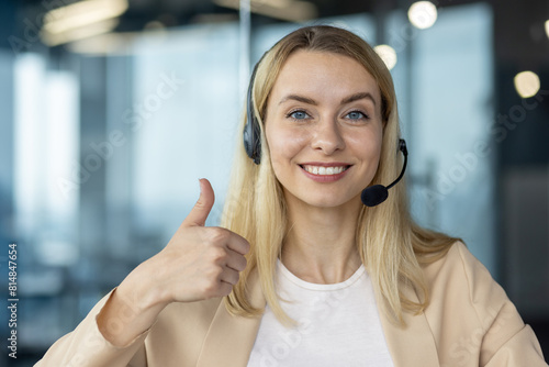 Smiling customer service representative with thumbs up, wearing a headset in a modern office setting