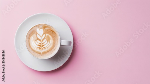  A pink background with a cup of cappuccino and a leaf in the foam on a saucer
