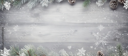 A frame made of festive fir branches perfectly encircles a blank Christmas card against the backdrop of a vintage gray board creating an ideal copy space image