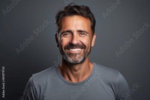 Portrait of a content man in his 40s smiling at the camera on pastel gray background