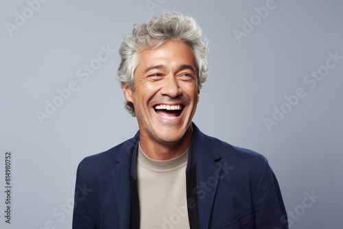 Portrait of a joyful man in his 50s laughing isolated in pastel gray background