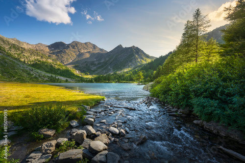 Trees and rocks along the shores of Lake Arpy at sunset. Aosta Valley, Italy