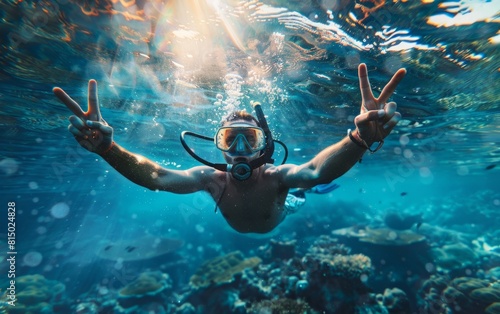 Snorkeler flashing peace signs underwater in a sunlit coral reef.