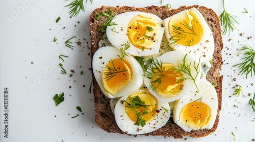 Simple and healthy open-faced sandwich with sliced boiled eggs and fresh herbs on dark rye bread.