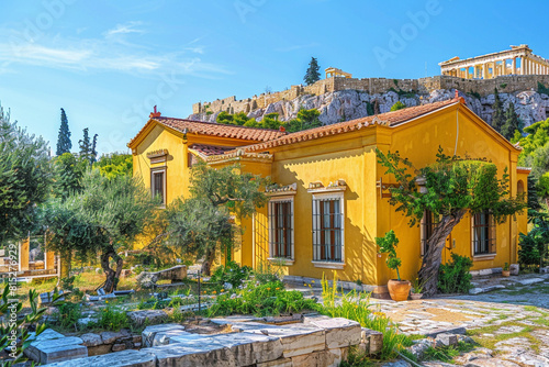 An ochre yellow house with Byzantine architecture, nestled in the shadow of the Acropolis in Athens, with olive trees and ancient ruins surrounding.