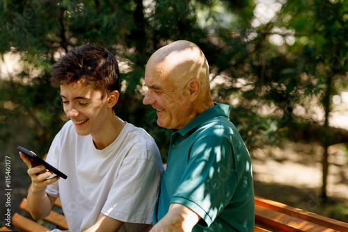 Portrait of senior man with his grandson using mobile