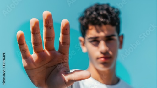 Close up of a young man displaying hand against blue backdrop