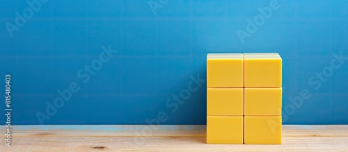 A yellow cube calendar is placed on a blue wooden surface providing ample copy space for additional content