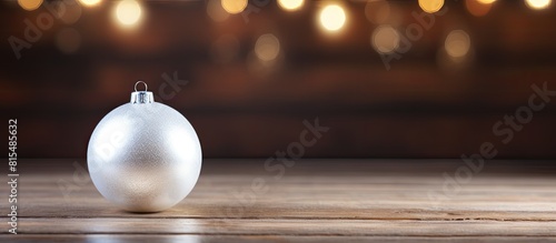 A festive white Christmas ornament can be seen on a rustic wooden background perfect for a copy space image