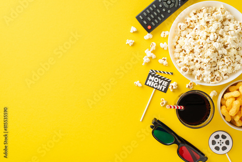 Cozy cinema experience at home with snacks and essentials for movie night. Top view yellow background adorned with movie-themed decor. Ideal for intimate gathering. Empty space for text or advertising