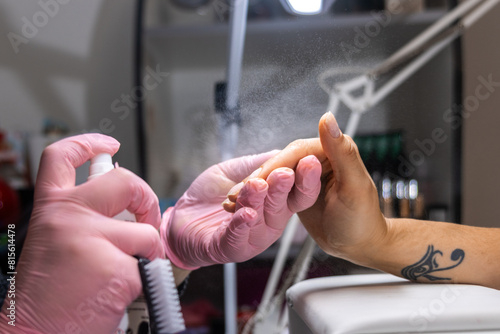 Manicurist securing manicure with fixative spray