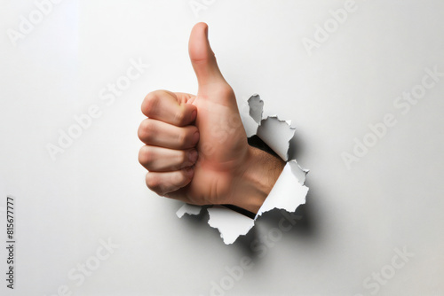 hand showing thumbs up sign sticking out of torn paper wall Isolated on white background