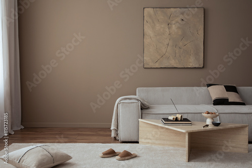 Warm and cozy living room interior with mock up poster frame, painting, beige sofa, travertine coffee table, slippers, bowl with nuts, plaid, pillow and personal accessories. Home decor. Template.