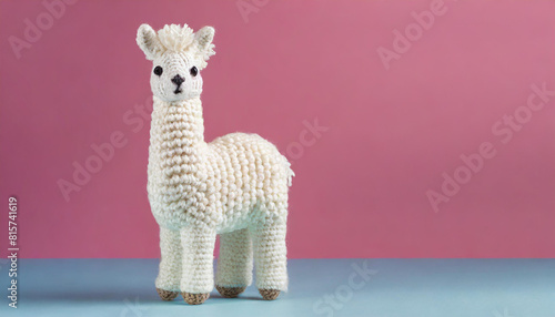 Soft alpaca plushie doll. Craft crocheted toy for kids. Handmade llama standing on pink background.
