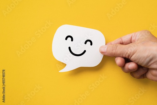 Hand hold happy face on real speech bubbles to each other. Giving good words to each other or giving positive feedback satisfaction from good customer feedback reviews