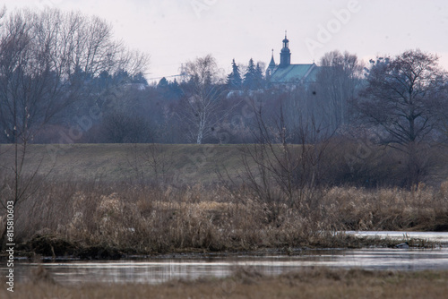 karajobraz z misteczkiem i chmurami w tle i rzeką na pierwszym planie