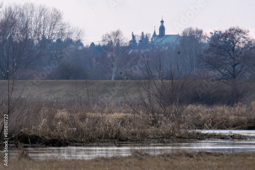 karajobraz z misteczkiem i chmurami w tle i rzeką na pierwszym planie