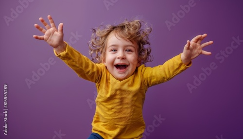 Boisterous toddler leaping with joyful abandon, all smiles against a bold royal purple.