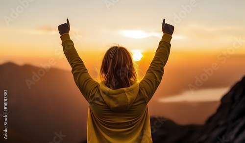 Young independent woman flexing her arms outdoor in mountains at sunset. Accomplishment, determination and self confident concept.