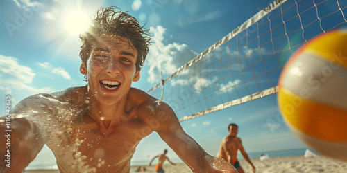 Male teen volleyball player catching the ball on a beach on a sunny day. Teenage friends playing beach volleyball together. Active leisure for kids.